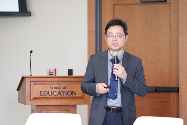 Presenter holding a microphone at an education event.